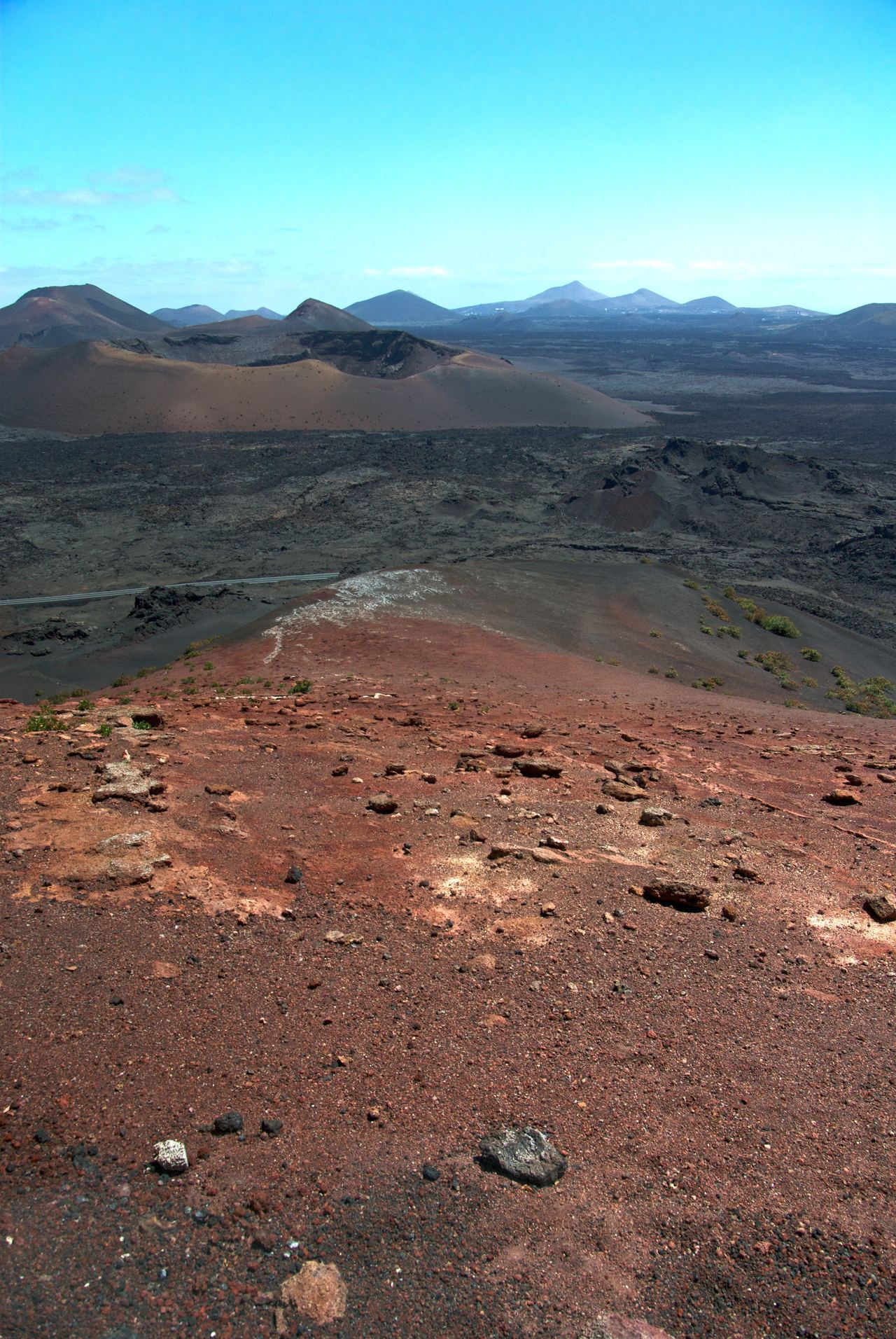 Blick über rote Vulkanerde auf die Krater von Timanfaya