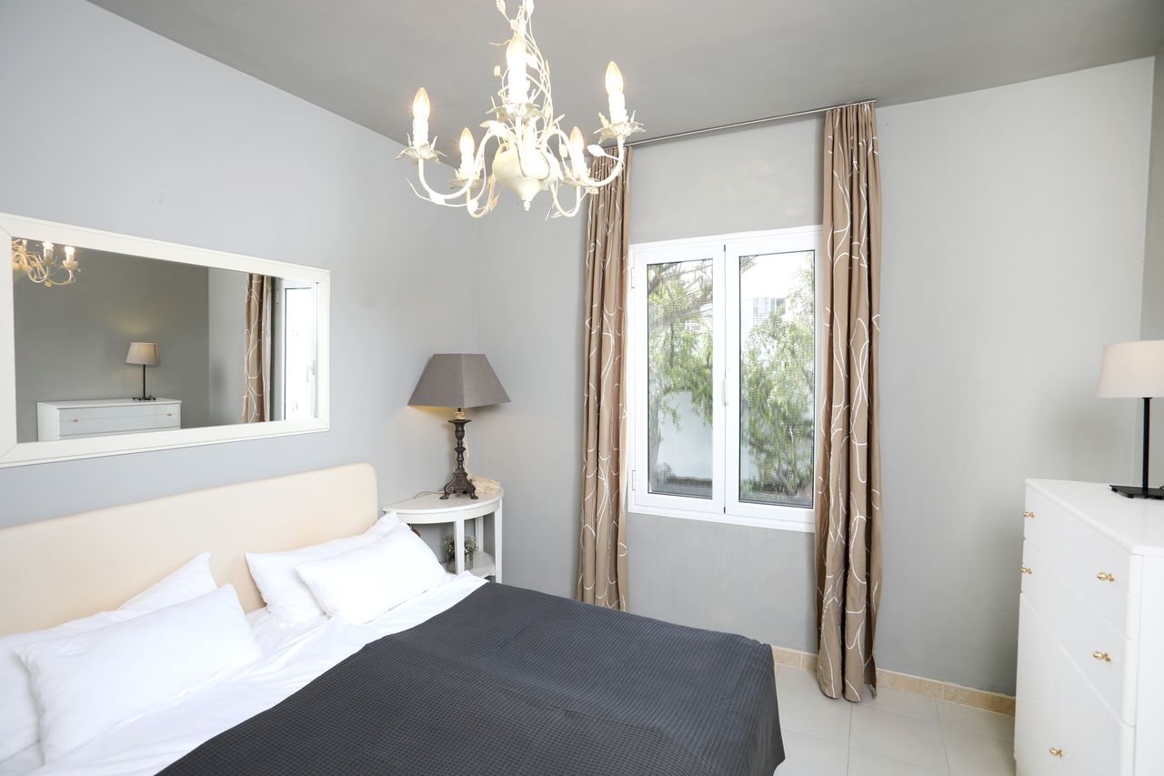 The grey bedroom with double bed and chandelier