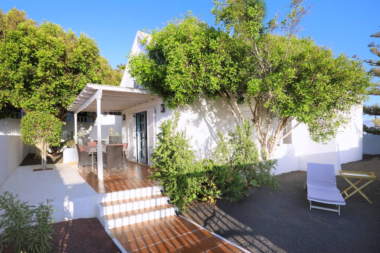 Casa Karen: white house with pergola and lush garden under a blue sky