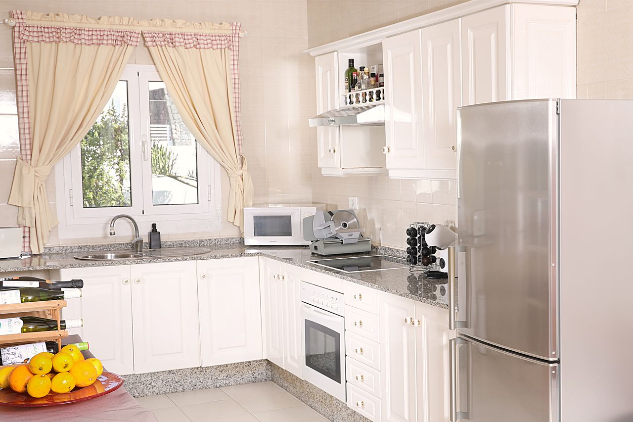 Bright country-style kitchen with granite worktop and a window onto the garden