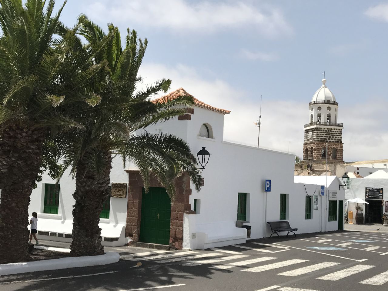 Street with palm trees and church tower in Teguise