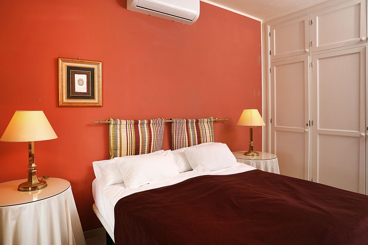 The red bedroom with fitted wardrobe and brass lamps